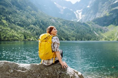 Aktif kadın görkemli dağların ve gölün güzel manzarasının tadını çıkarıyor. Seyahat, macera. Etkin bir yaşam biçimi kavramı.