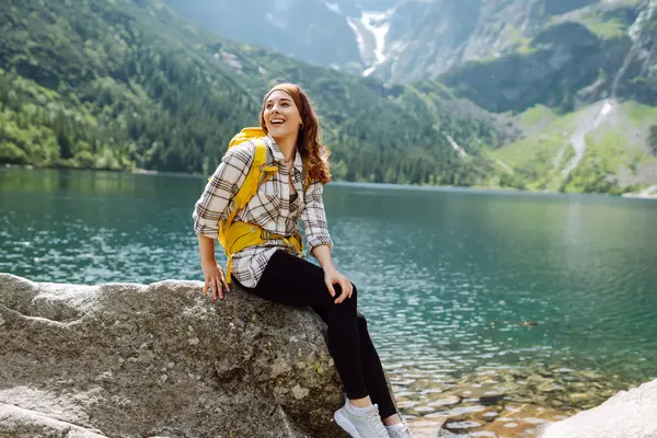 Active woman enjoys the beautiful scenery of the majestic mountains and lake. Travel, adventure. Concept of an active lifestyle.