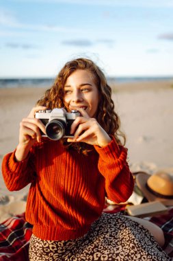 Sahilde yürüyen ve fotoğraf çeken genç bir kadın doğanın güzelliğini yakalıyor. Seyahat blogu. Macera, tatil konsepti.