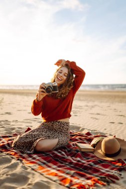 Sahilde yürüyen ve fotoğraf çeken genç bir kadın doğanın güzelliğini yakalıyor. Seyahat blogu. Macera, tatil konsepti.