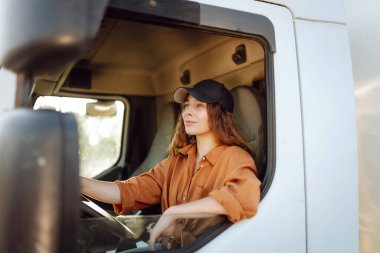 Büyük bir kamyon kullanan genç ve güzel bir kadının portresi. Aracın içinde. Halk ve endüstriyel ulaşım kavramı.