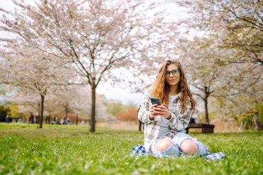 Genç bayan dışarıda cep telefonuyla mesajlaşıyor. Bloglama, iletişim, çevrimiçi.