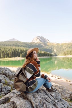 Mutlu kadın güneşli havada dağ gölü manzarasının tadını çıkarıyor. Seyahat, doğa, tatil kavramı. Etkin yaşam biçimi.