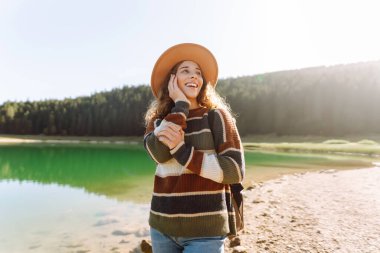 Mutlu kadın güneşli havada dağ gölü manzarasının tadını çıkarıyor. Seyahat, doğa, tatil kavramı. Etkin yaşam biçimi.