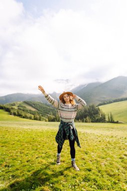 Sırt çantalı bir kadın turist dağlarda rahatça dolaşır. Gezgin doğanın tadını çıkarıyor. Maceralar.