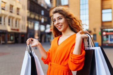 Alışveriş yapan bir kadın. Alışveriş yaptıktan sonra şehirde dolaşan siyah elbiseli moda kadını. Kara Cuma, satış, tüketici, yaşam tarzı konsepti.