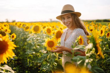Genç bir kadın ayçiçeği tarlasında yürüyor. Moda, yaşam tarzı, seyahat ve tatil kavramı.