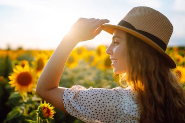 Genç bir kadın ayçiçeği tarlasında yürüyor. Moda, yaşam tarzı, seyahat ve tatil kavramı.