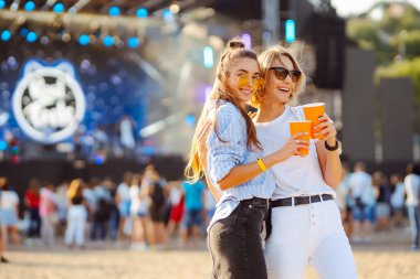 Plaj partisinde bira içen iki genç kadın. Müzik festivali. Yaz tatili, tatil konsepti.