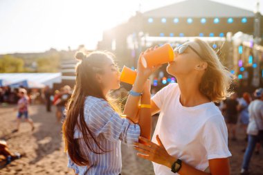 Plaj partisinde bira içen iki genç kadın. Müzik festivali. Yaz tatili, tatil konsepti.