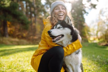 İri yarı bir köpeğe sahip bir kadın parkta yürürken gülümseyerek sevgili köpeğini okşar. Eğlence anlayışı, eğlence.