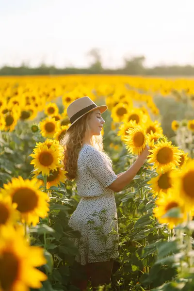 Genç bir kadın ayçiçeği tarlasında yürüyor. Moda, yaşam tarzı, seyahat ve tatil kavramı.