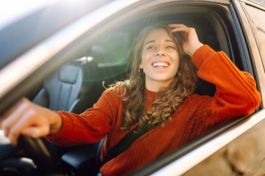 Genç bir kadının portresi araba sürüyor ve gülümsüyor. Araba yolculuğu, yaşam tarzı konsepti..