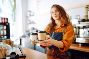 Elinde hazır kahve tutan genç bir baristanın portresi. Paket yemek. İş konsepti.