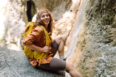 Sırt çantalı ve bastonlu genç bir kadın doğa yürüyüşü yapıyor. Macera, seyahat, turizm, yürüyüş ve insan konsepti.