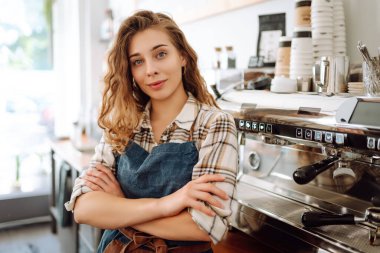 Modern bir kafe barında önlük giymiş güzel bir baristanın portresi. İş konsepti, yiyecek ve içecekler.