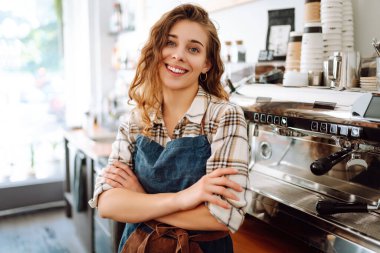 Modern bir kafe barında önlük giymiş güzel bir baristanın portresi. İş konsepti, yiyecek ve içecekler.