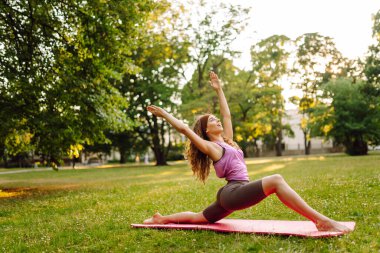 Yoga yapan genç bir kadın, parkta spor egzersizleri. Sağlıklı spor yaşam tarzı.