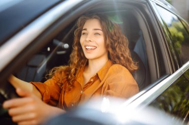 Genç bir kadının portresi araba sürüyor ve gülümsüyor. Otomobil yolculuğu. Aynı arabayı paylaşıyoruz. Yaşam tarzı kavramı.