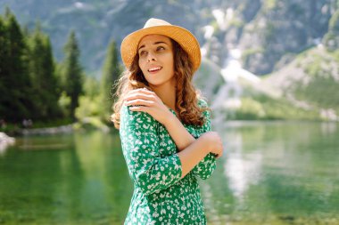 Yeşil elbiseli güzel kadın güneşli bir günde dağlarda eğleniyor. Moda, güzellik, yaşam tarzı, seyahat kavramı.