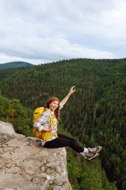 Kadın turist dağın tepesinde doğa manzarasının tadını çıkarıyor. Yaşam tarzı, macera, doğa, aktif yaşam.