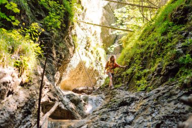 Sarı sırt çantalı maceraperest kadın dağ manzarasının arka planında yürüyüş parkurunda yürüyor. Doğa, aktif yaşam.