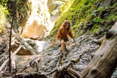 Sarı sırt çantalı maceraperest kadın dağ manzarasının arka planında yürüyüş parkurunda yürüyor. Doğa, aktif yaşam.