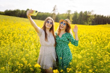 Seyahat ederken selfie. Çiçek tarlasında yürürken iki kadın selfie çeker. Moda, güzellik konsepti. 