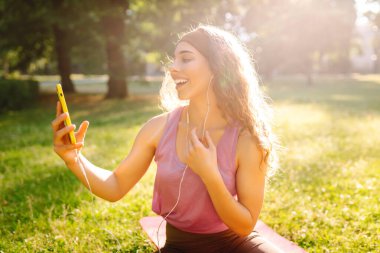 Gelişim, performans ve sağlıklı bir yaşam tarzı için iletişim için akıllı telefonu olan genç bir bayan sporcu. Spor, aktif yaşam, sağlıklı yaşam tarzı.