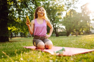 Gelişim, performans ve sağlıklı bir yaşam tarzı için iletişim için akıllı telefonu olan genç bir bayan sporcu. Spor, aktif yaşam, sağlıklı yaşam tarzı.