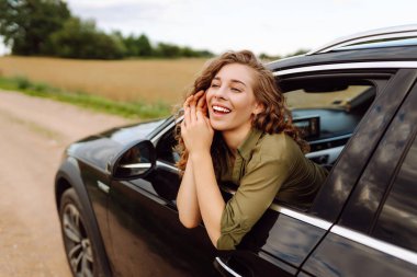Güzel bir kadın dinleniyor ve araba penceresinden dışarı çıkmaktan zevk alıyor. Yaşam tarzı, hafta sonu, turizm, doğa, aktif yaşam.