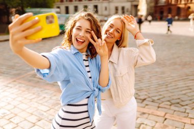 Sokakta yürürken selfie çeken mutlu kadınlar. Moda, seyahat, teknoloji, blog konsepti.