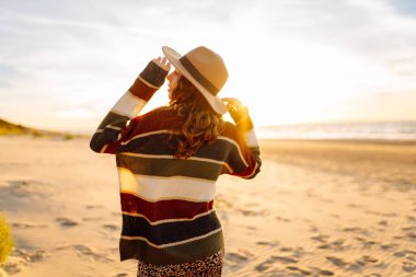 Gün batımında denizde yürüyen genç bir kadın. Seyahat, hafta sonu, rahatlama ve yaşam tarzı konsepti.