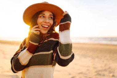 Gün batımında denizde yürüyen genç bir kadın. Seyahat, hafta sonu, rahatlama ve yaşam tarzı konsepti.
