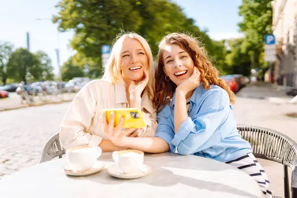 Две Молодые Женщины Сидят Кафе Наслаждаются Кофе Веселятся Смартфоном Перерыв — стоковое фото