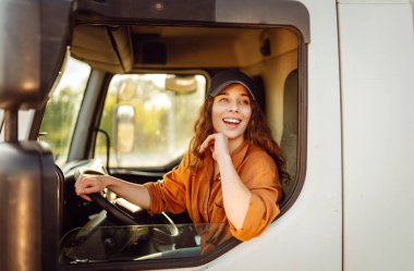 Büyük bir kamyon süren profesyonel bir kadının portresi. Aracın içinde. Kadın bir kamyoncu. Halk ve endüstriyel ulaşım kavramı.