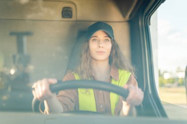 Büyük bir kamyon süren profesyonel bir kadının portresi. Aracın içinde. Kadın bir kamyoncu. Halk ve endüstriyel ulaşım kavramı.