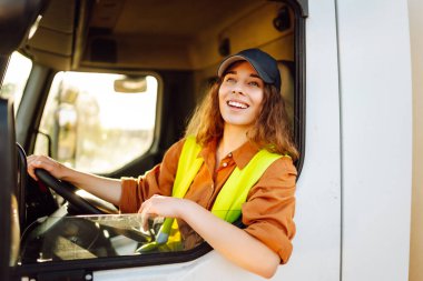 Büyük bir kamyon süren profesyonel bir kadının portresi. Aracın içinde. Kadın bir kamyoncu. Halk ve endüstriyel ulaşım kavramı.