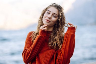 Rüzgarlı bir günde güzel bir kıvırcık kadının portresi. Seyahat, moda, rahatlama ve yaşam tarzı konsepti.