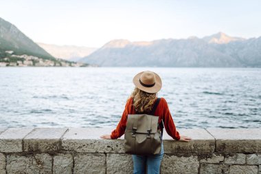 Genç bayan turist güzel göl, ağaçlar ve dağ manzarasının tadını çıkarıyor. Arkadan bak. Yaşam tarzı, seyahat, turizm, doğa, aktif yaşam.