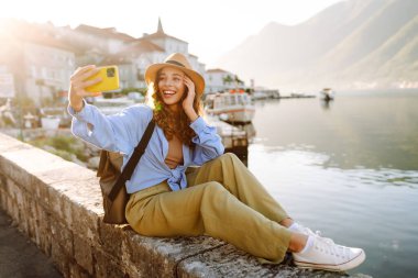 Güzel bir turist sokakta yürüyüp akıllı telefon kamerasıyla selfie çekiyor. Yaşam tarzı, seyahat, dinlenme, hafta sonu, aktif yaşam.
