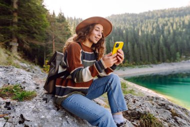 Genç bayan turist doğada akıllı telefon kullanıyor. Yaşam tarzı, seyahat, turizm, aktif yaşam.