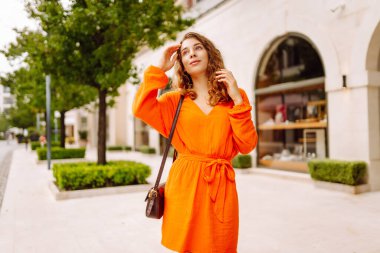 Şehir sokaklarında yürüyen parlak elbiseli güzel bir kadının portresi. Yaşam tarzı, moda, seyahat kavramı.