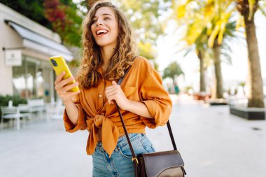 Sokakta akıllı telefon kullanan genç bir kadın. İş, teknoloji, blog, iletişim kavramı.