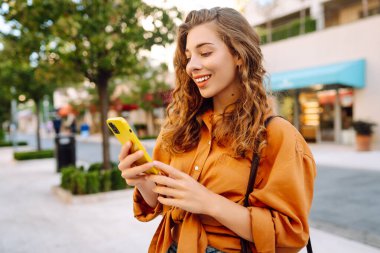 Sokakta akıllı telefon kullanan genç bir kadın. İş, teknoloji, blog, iletişim kavramı.