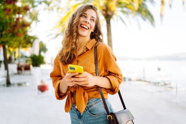 Sokakta akıllı telefon kullanan genç bir kadın. İş, teknoloji, blog, iletişim kavramı.