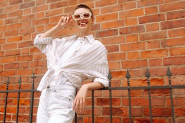 Şehir sokaklarında poz veren kısa saçlı bir kadının portresi. Kadın turistler Avrupa sokaklarının kentsel atmosferinin tadını çıkarıyor.