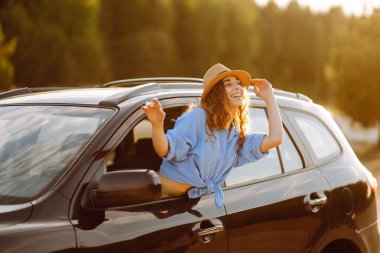 Maceraya doğru. Yaz tatili seyahatinde araba camından sarkan mutlu kadın. Yaşam tarzı, seyahat, doğa, aktif yaşam.