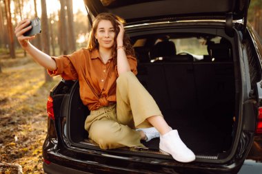 Arabayla seyahat ederken selfie. Video aracılığıyla mutlu turist sohbetleri ya da arabanın arka koltuğunda selfie çekmeler. Arabayla seyahat etme kavramı, aktif yaşam tarzı.