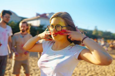 Gökkuşağı renkli tozla kaplı mutlu kadın Holi renk festivalini kutluyor. Genç bir kadın açık havada renkli tozla eğleniyor. Plaj partisi. Geleneksel Hint tatili.